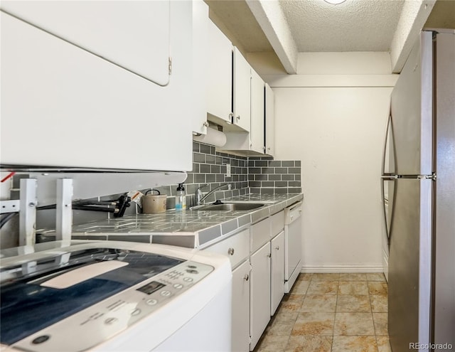 kitchen featuring tile countertops, dishwasher, white cabinets, sink, and stainless steel refrigerator