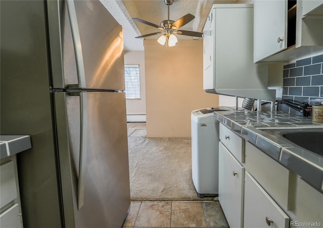 kitchen featuring light carpet, stainless steel fridge, backsplash, ceiling fan, and white cabinets