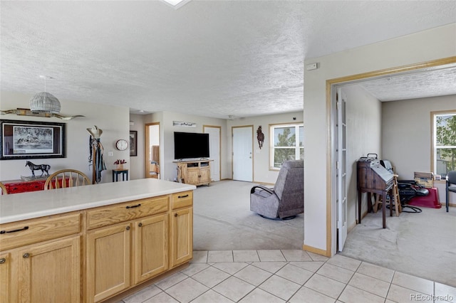 kitchen featuring light carpet, open floor plan, a textured ceiling, light tile patterned floors, and light countertops