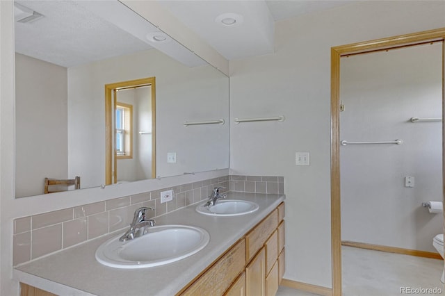 bathroom with backsplash, double vanity, baseboards, and toilet