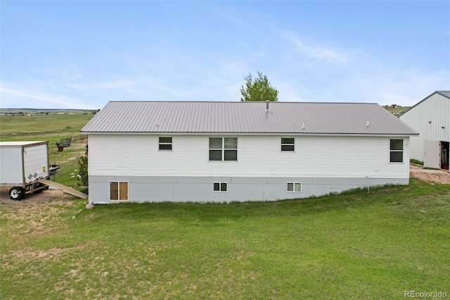 back of house featuring a lawn and metal roof