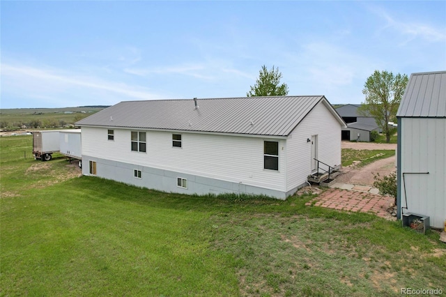 back of house with a lawn and metal roof