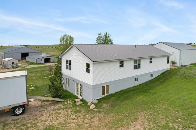 back of property featuring a lawn and metal roof