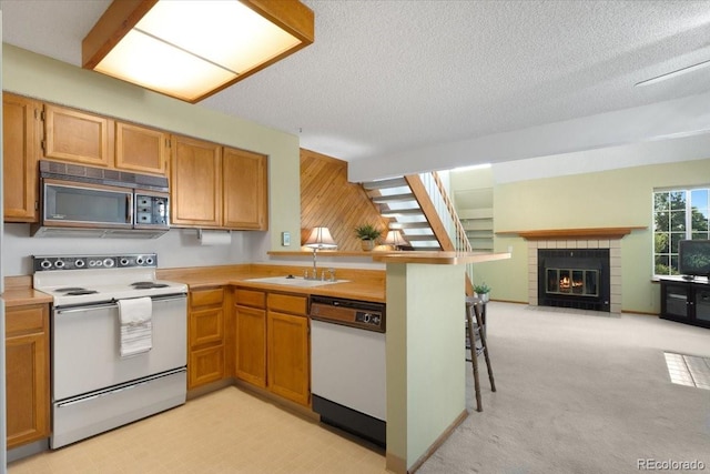 13873 E Lehigh Ave Unit E, Aurora, CO 80014 - kitchen featuring white appliances, light countertops, a fireplace with flush hearth, a peninsula, and open floor plan