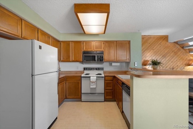 13873 E Lehigh Ave Unit E, Aurora, CO 80014 - kitchen with white appliances, a peninsula, brown cabinetry, light countertops, and light floors