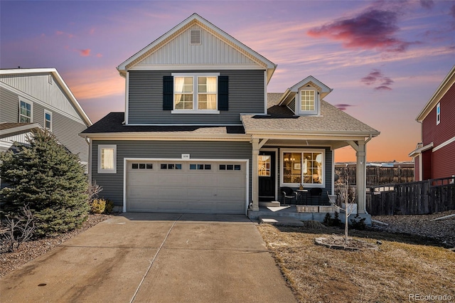 traditional-style home featuring driveway, roof with shingles, an attached garage, covered porch, and fence