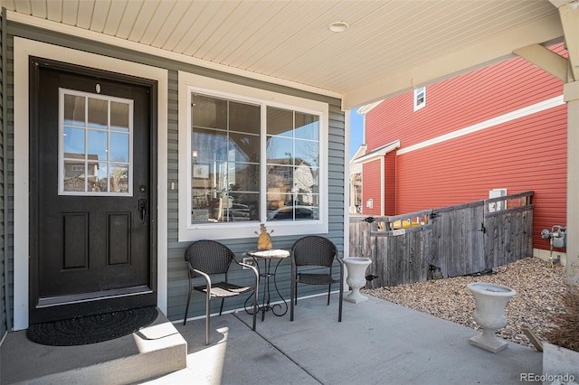 view of exterior entry with covered porch and fence