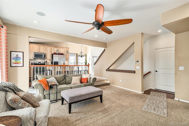 living area with recessed lighting, ceiling fan with notable chandelier, baseboards, and light colored carpet