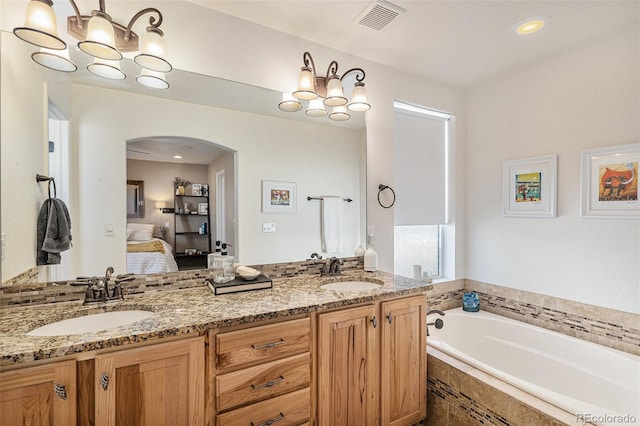 bathroom with a garden tub, ensuite bath, a sink, and visible vents