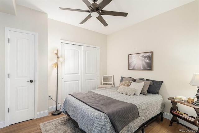 bedroom with ceiling fan, a closet, baseboards, and wood finished floors