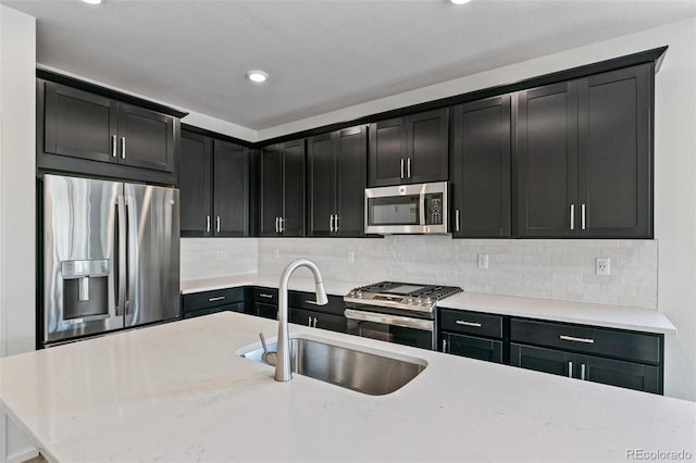 kitchen with appliances with stainless steel finishes, backsplash, light stone counters, and sink