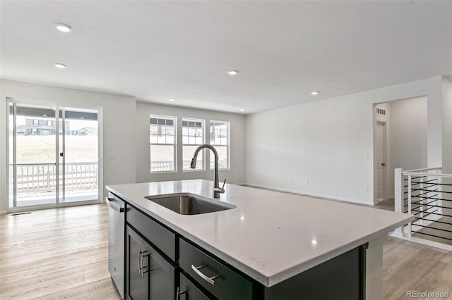 kitchen with a wealth of natural light, light wood-type flooring, a kitchen island with sink, and sink