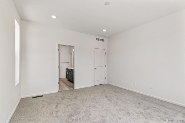 unfurnished bedroom with connected bathroom and light colored carpet