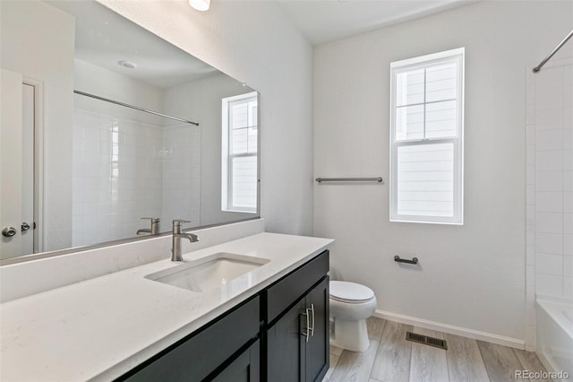 full bathroom featuring a wealth of natural light, hardwood / wood-style floors, vanity, and toilet