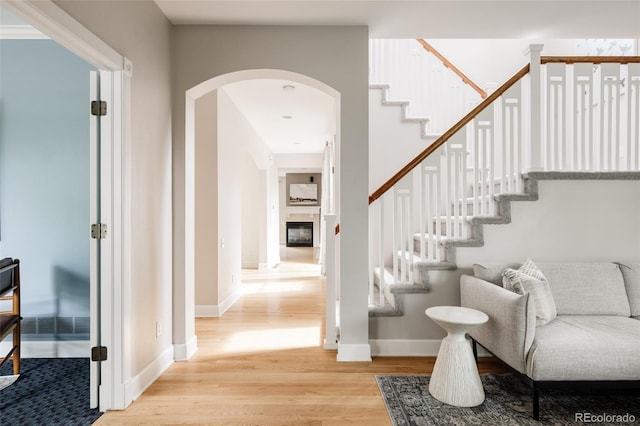 8122 E 6th Pl, Denver, CO 80230 - stairway featuring wood finished floors, arched walkways, a glass covered fireplace, and baseboards