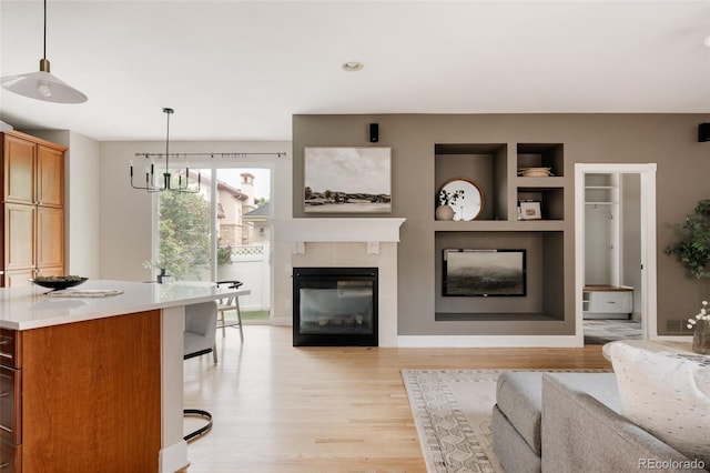 8122 E 6th Pl, Denver, CO 80230 - living room with light wood-style flooring, a glass covered fireplace, a chandelier, recessed lighting, and built in features