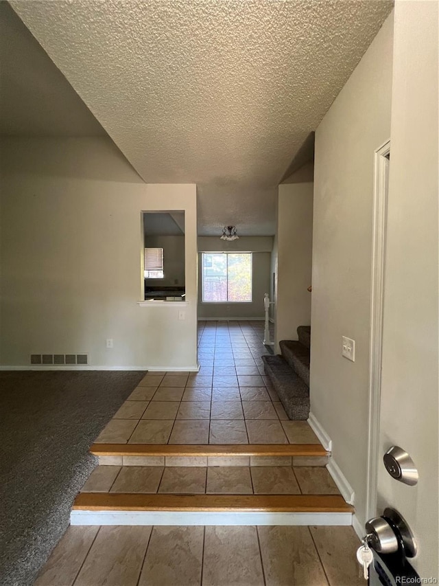 hallway featuring a textured ceiling and tile patterned floors