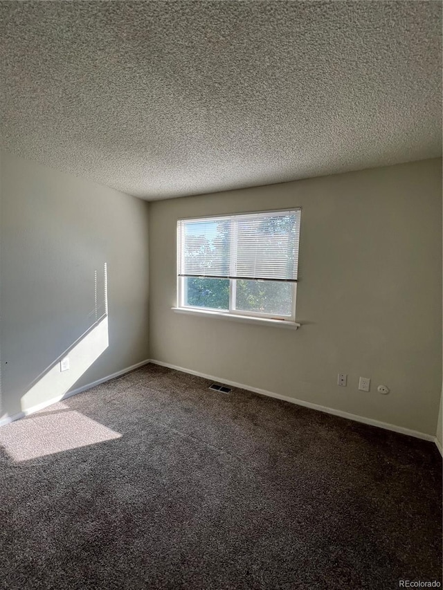 empty room with a textured ceiling and carpet flooring