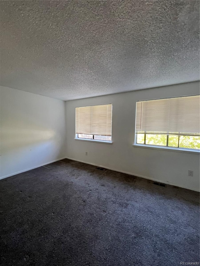 empty room with a textured ceiling and dark carpet