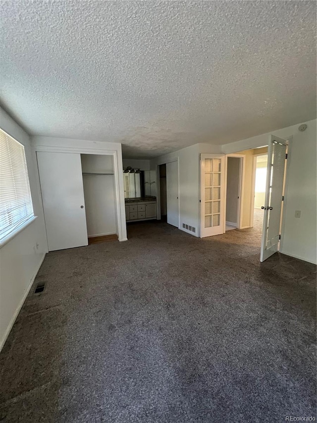 interior space featuring a textured ceiling and dark colored carpet