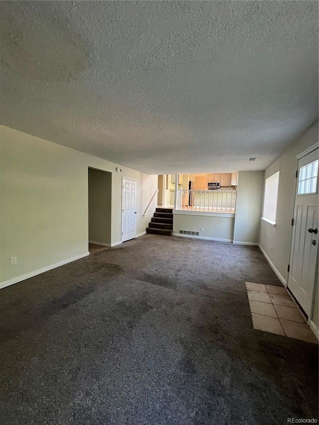 unfurnished living room featuring carpet and a textured ceiling