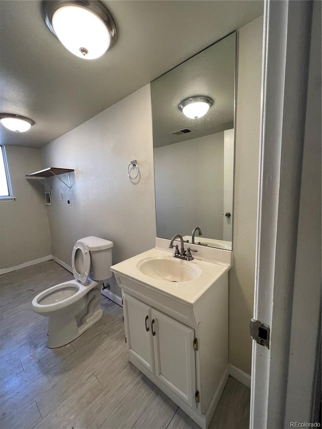 bathroom with vanity, toilet, and hardwood / wood-style flooring