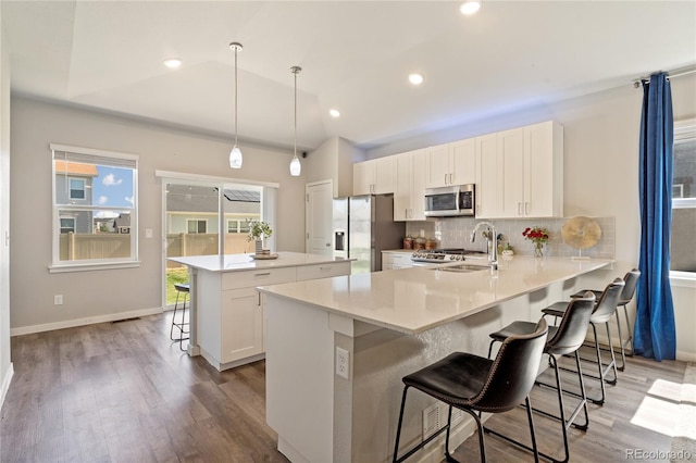 kitchen with pendant lighting, sink, a breakfast bar, appliances with stainless steel finishes, and kitchen peninsula