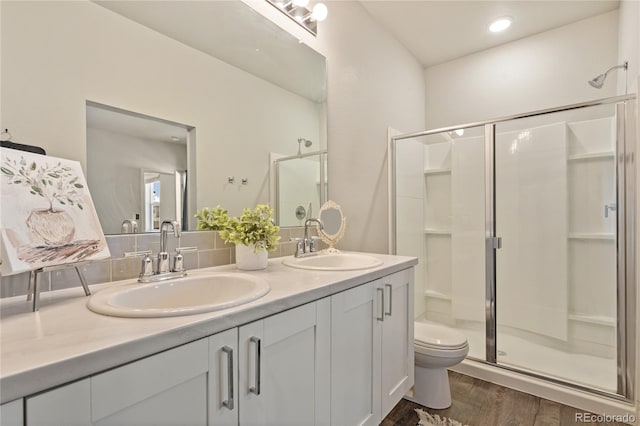 bathroom with wood-type flooring, toilet, a shower with door, and vanity