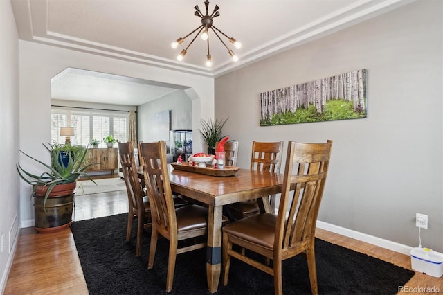 dining space with hardwood / wood-style floors, a tray ceiling, and a chandelier