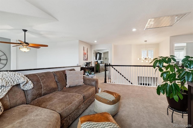 carpeted living room with ceiling fan with notable chandelier