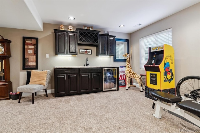 bar with sink, light colored carpet, and wine cooler