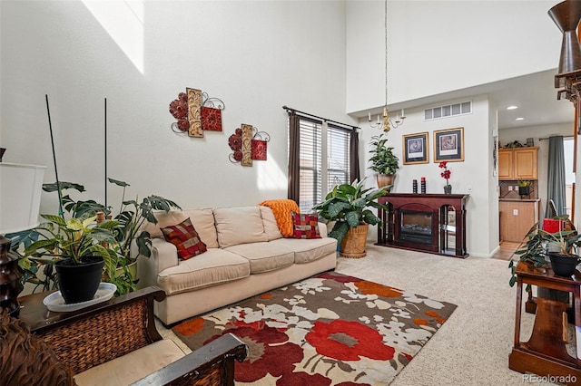 carpeted living area with visible vents, a towering ceiling, and a fireplace