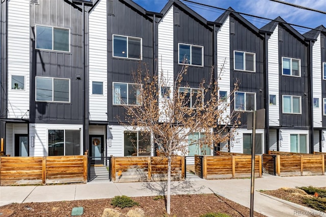 townhome / multi-family property featuring a fenced front yard, board and batten siding, and a gate