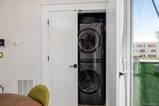 clothes washing area with stacked washer / dryer, laundry area, and visible vents