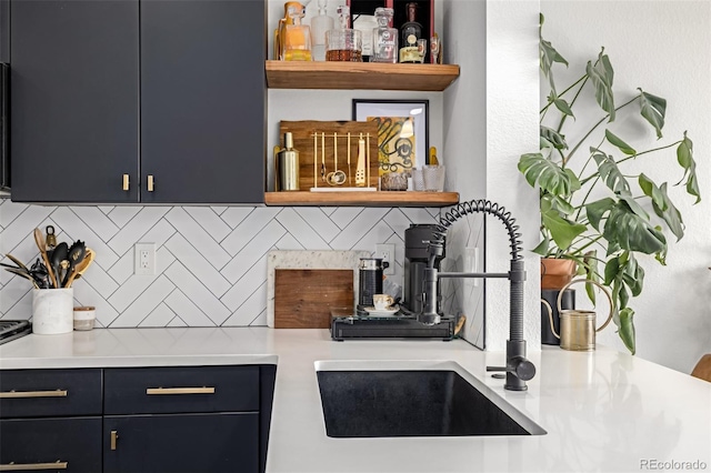 kitchen with tasteful backsplash, a sink, light countertops, and open shelves