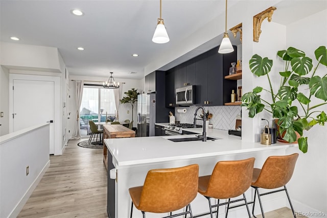 kitchen featuring dark cabinetry, open shelves, stainless steel appliances, decorative backsplash, and light countertops