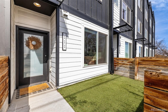 doorway to property featuring fence and board and batten siding