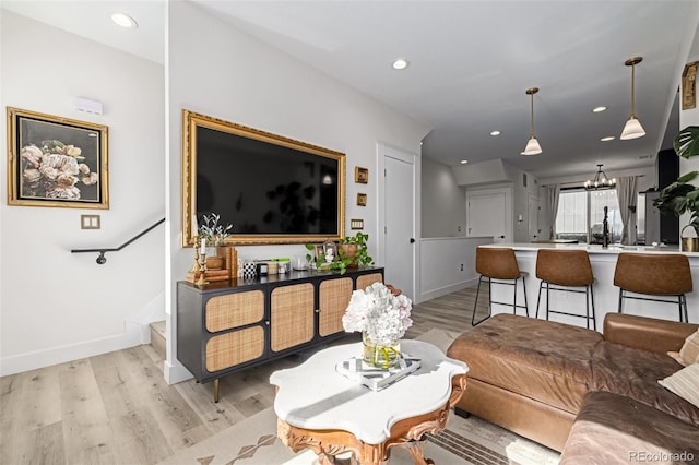 living room with recessed lighting, baseboards, light wood finished floors, and a chandelier