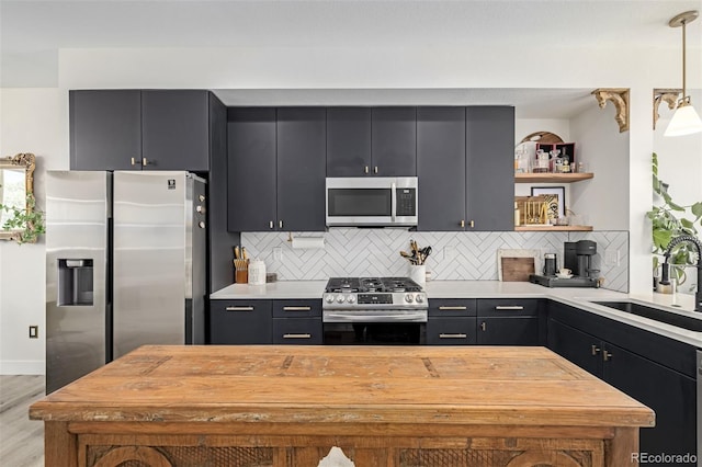 kitchen featuring light countertops, open shelves, appliances with stainless steel finishes, and a sink