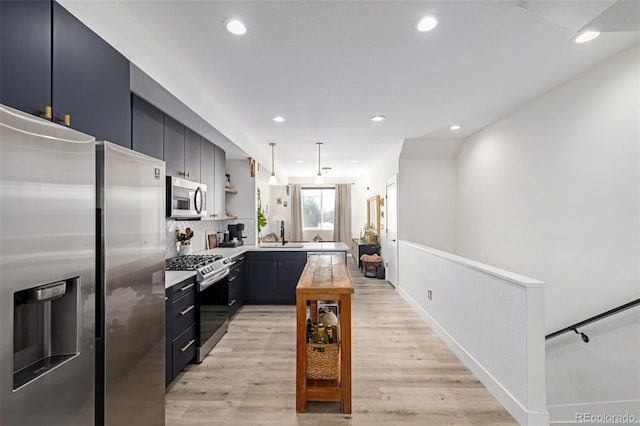 kitchen with light wood-type flooring, a sink, stainless steel appliances, a peninsula, and light countertops