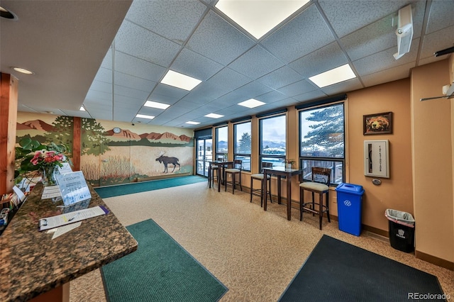 interior space featuring a paneled ceiling and baseboards