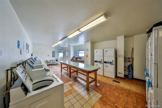 kitchen featuring light tile patterned flooring, a textured ceiling, and stacked washer / drying machine