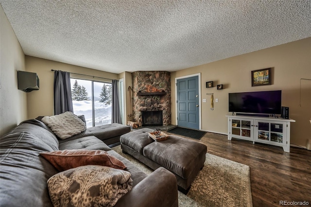 living area featuring a stone fireplace, a textured ceiling, and wood finished floors