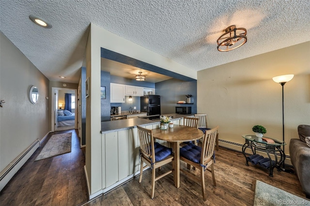 dining area featuring a baseboard heating unit, baseboards, a textured ceiling, and dark wood-style floors