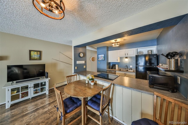 kitchen with dark wood finished floors, a peninsula, a sink, black appliances, and baseboard heating