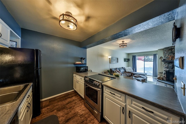 kitchen with dark countertops, black appliances, dark wood-style floors, a textured ceiling, and a sink