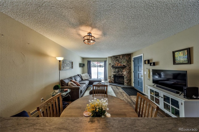 dining room with a textured ceiling, wood finished floors, a fireplace, and a textured wall