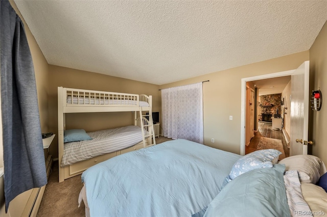 carpeted bedroom with baseboard heating and a textured ceiling