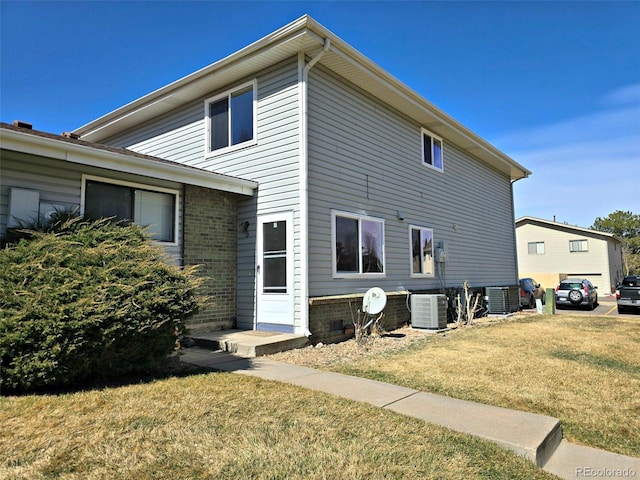 view of property exterior featuring cooling unit, a yard, and brick siding