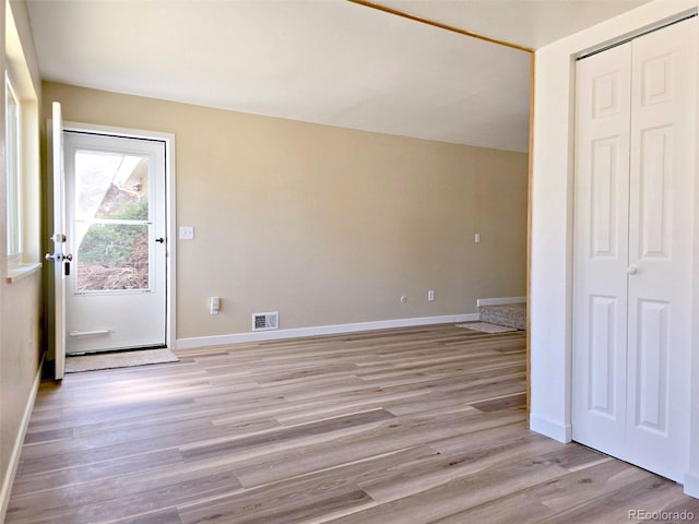 interior space featuring lofted ceiling, baseboards, visible vents, and light wood-type flooring